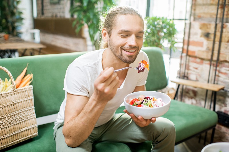 a man happily eating a salad to curb hunger