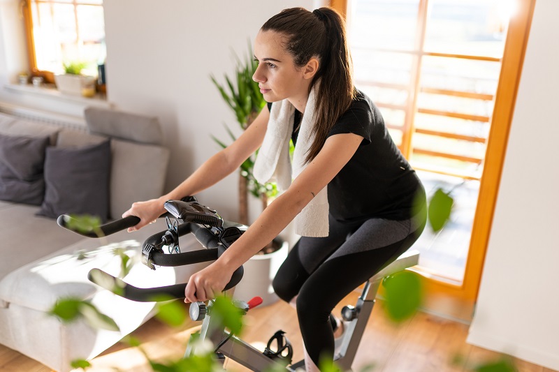 woman cycling on a stationary bike in her living room.