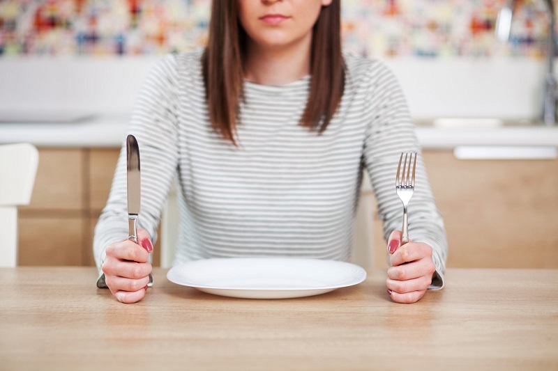 woman sitting in front of an empty plate. how to curb hunger