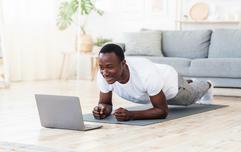 man working out at home in front of a laptop to curb hunger