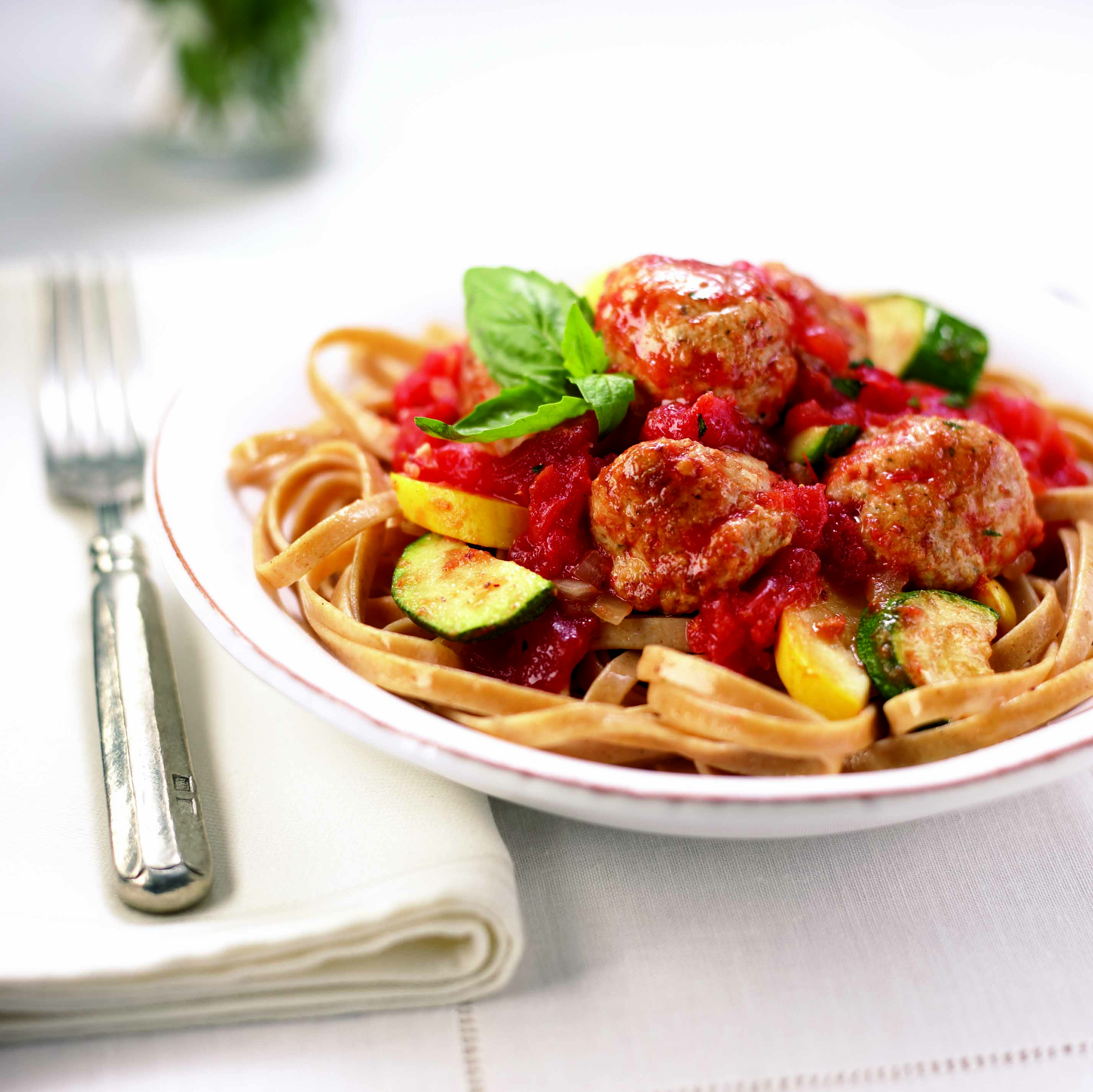 Meatballs with zucchini, squash and tomato sauce served over whole wheat pasta
