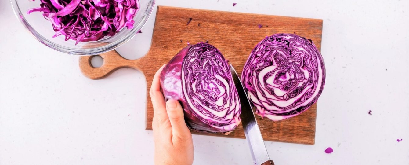 person cutting red cabbage on a cutting board
