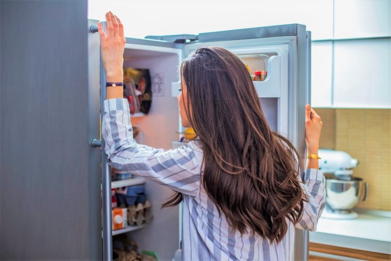 a woman looking into a fridge to curb hunger