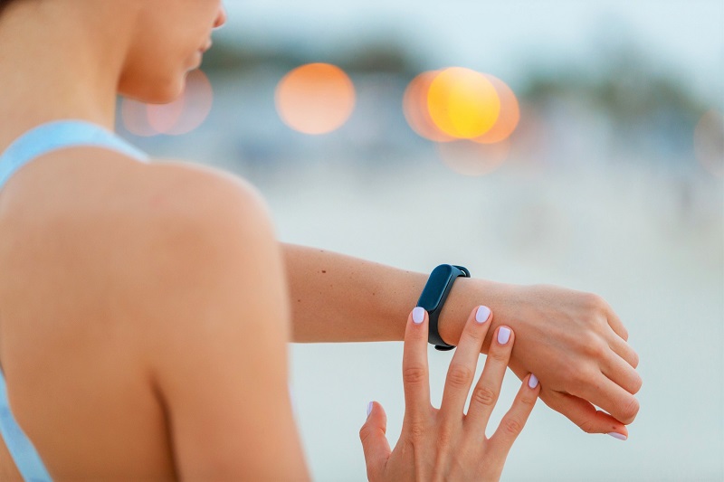 a woman looking at her fitness tracker while on a run