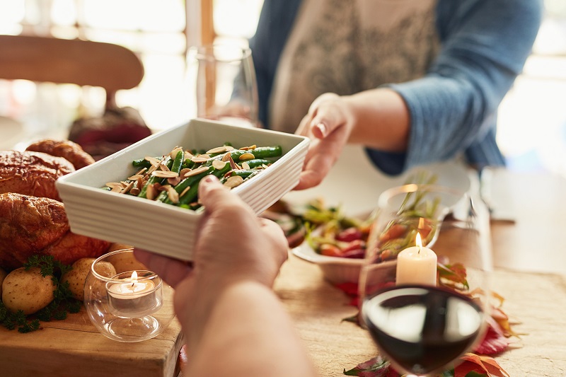 a man handing a woman a casserole over a dinner table. winter weight loss tips