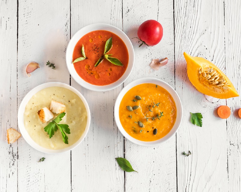 variety of healthy soups alongside fresh vegetables. winter weight loss tips