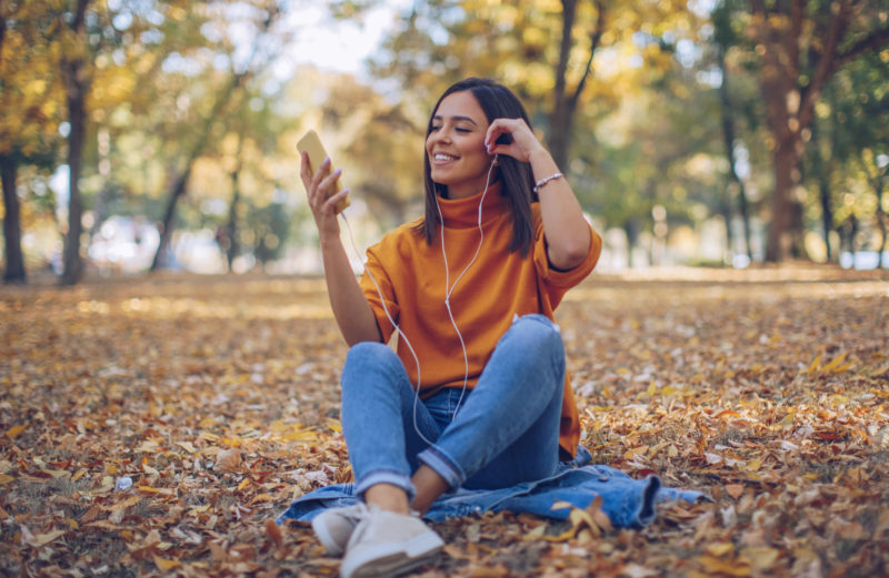 girl sitting outside in autumn with headphones