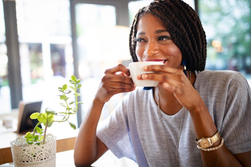 a woman drinking a cup of coffee or tea on a sunny day. low calorie drinks