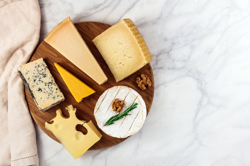 a variety of cheeses on a charcuterie board