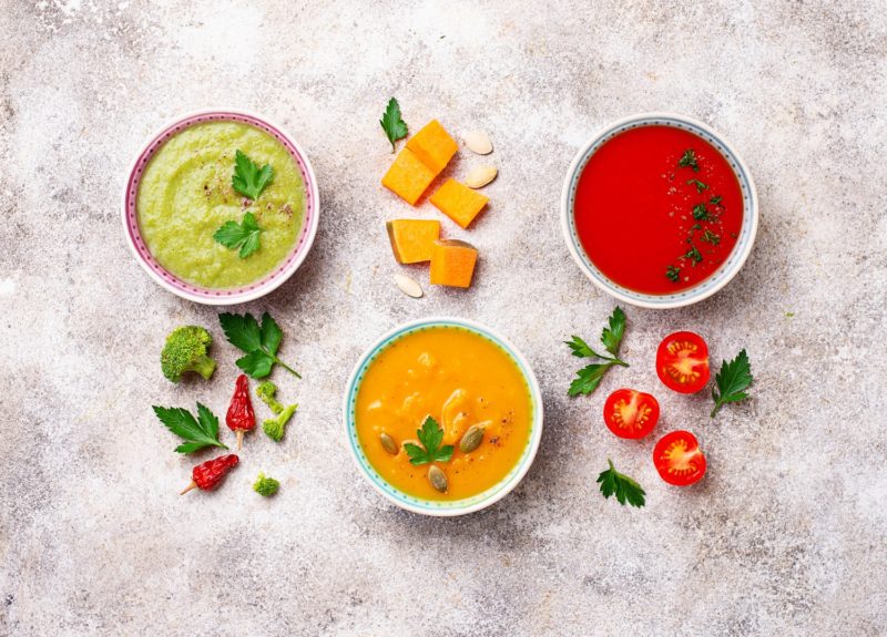 a display of three colorful low-carb soup recipes decorated with accent vegetables