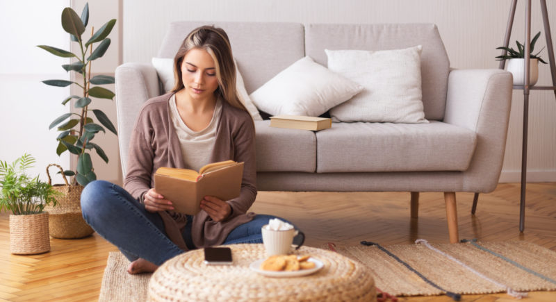 Woman practicing self care at home with a book and coffee