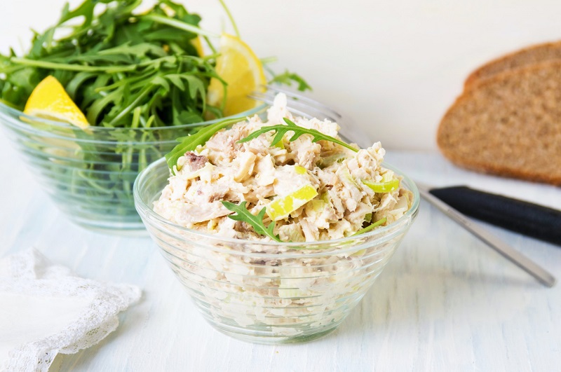 bowl of rotisserie chicken salad with arugula and lemon