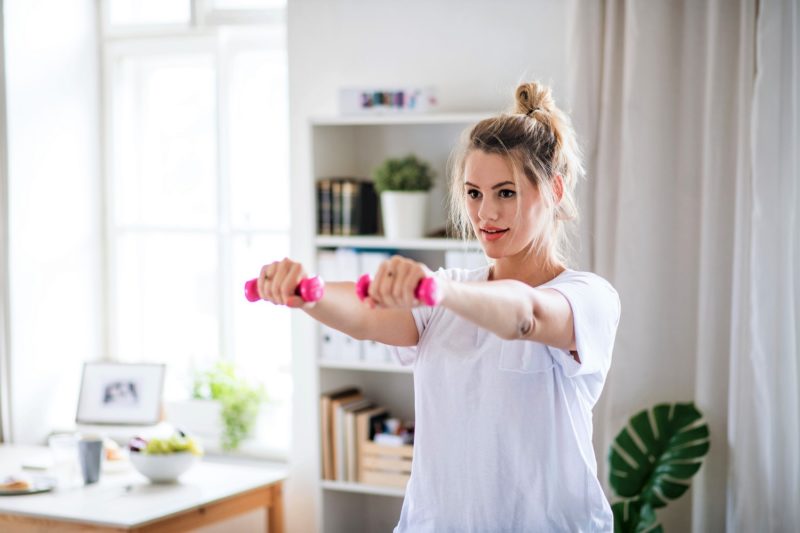 woman doing dumbbell strength training exercise in home