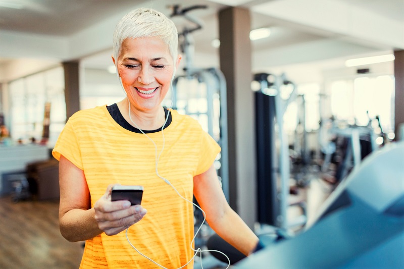 woman Exercising on treadmill in the gym and using smart phone