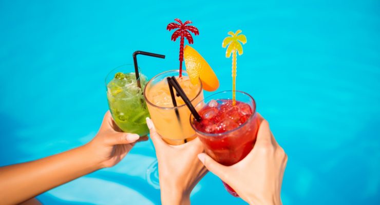 three women drinking cocktails by the pool on vacation